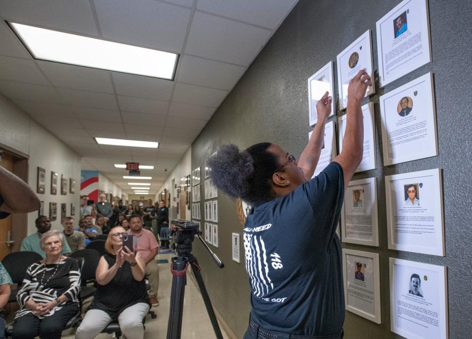 Corrections officer trainee Regina Ray hangs a photo of her late grandfather, Escambia County Sheriff's Office Deputy Morley "Buddy" Ray, during a ceremony Tuesday dedicating the new Wall of Tribute at the George Stone Criminal Justice Training Center in Pensacola. The wall honoring fallen officers from the four area counties was created by the 118th class of corrections officer trainees. Buddy Ray was shot and killed in 1978 during a store robbery while moonlighting as a security guard.