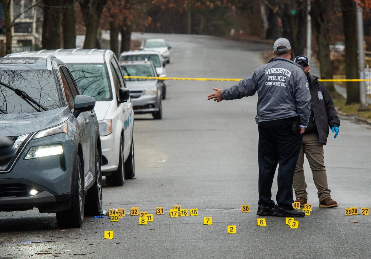 Detectives placed evidence markers near a car that is part of the investigation.