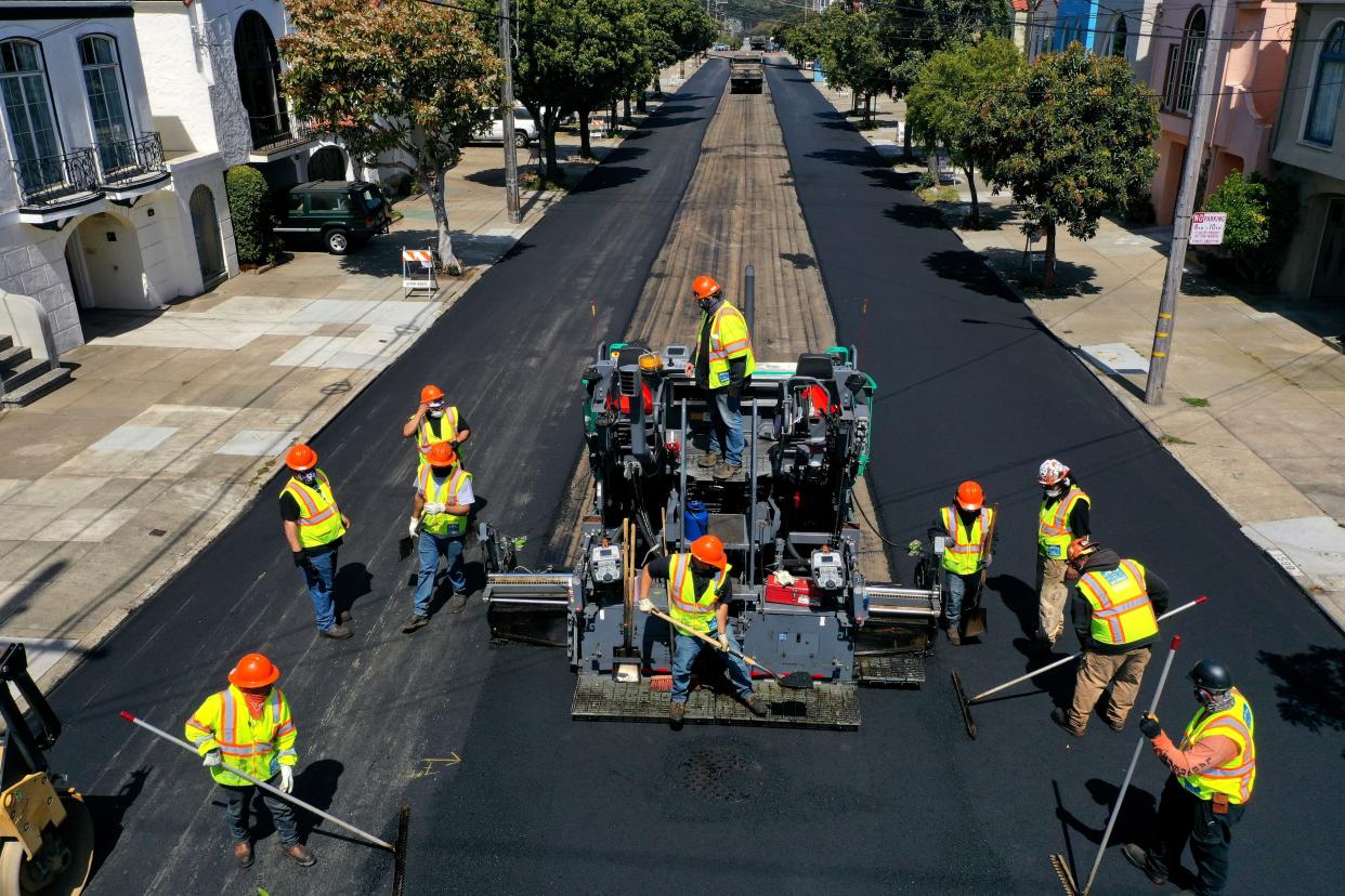 In an aerial view, workers with the San Francisco Department of Public Works repave a section of 24th Avenue in San Francisco, California. 