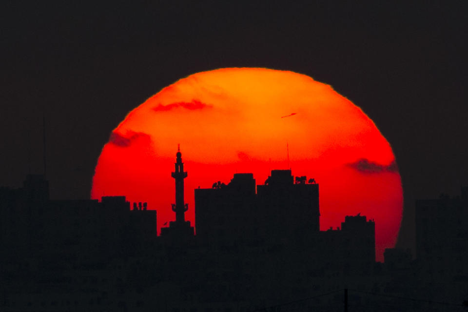 The sun sets behind a mosque and buildings in the Gaza Strip, Tuesday, May 15, 2018. (AP Photo/Ariel Schalit)