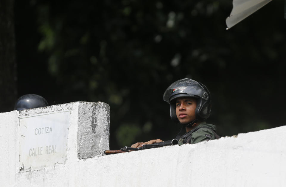 FILE - In this Jan. 21, 2019 file photo, a loyal National Guard soldier looks out to the street from behind his base's wall after an apparent mutiny by some of his fellow guards in the Cotiza neighborhood of Caracas, Venezuela. The disturbance started after a group of men dressed in military fatigues and carrying assault weapons published a series of videos on social media saying they won't recognize President Nicolas Maduro's government. (AP Photo/Fernando Llano, File)