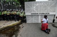A woman kneels during a silent march by the opposition in a show of condemnation of the government of Venezuelan President Nicolas Maduro, in Caracas