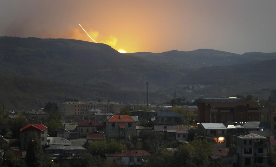 Explosions are seen behind the mountains during a military conflict outside Stepanakert, the separatist region of Nagorno-Karabakh, Friday, Oct. 30, 2020. The Azerbaijani army has closed in on a key town in the separatist territory of Nagorno-Karabakh following more than a month of intense fighting. (AP Photo)
