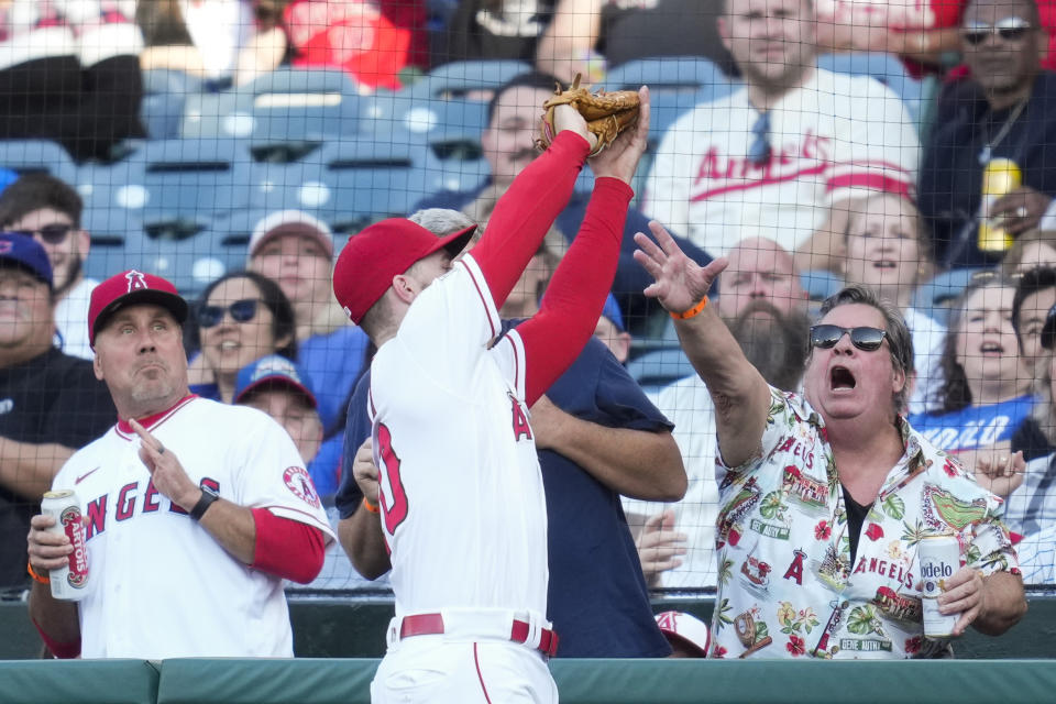 A fan reaches for a foul ball as Los Angeles Angels first baseman Jared Walsh (20) makes the catch during the first inning of a baseball game against the Chicago Cubs in Anaheim, Calif., Wednesday, June 7, 2023. (AP Photo/Ashley Landis)