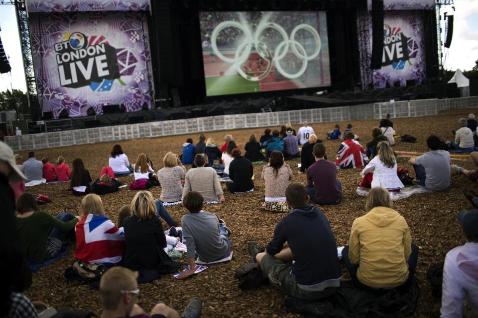 In this Monday, Aug. 6, 2012 photo, people watch a broadcast of the woman's 1500-meter semifinals on a screen at Hyde Park in London during 2012 Summer Olympics, in London. (AP Photo/Emilio Morenatti)