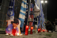 Candles lie next to a picture of Diego Armando Maradona outside the San Paolo Stadium to pay their homage to the late soccer legend, in Naples, Italy, Wednesday, Nov. 25, 2020. Diego Maradona has died. The Argentine soccer great was among the best players ever and who led his country to the 1986 World Cup title before later struggling with cocaine use and obesity. He was 60. (AP Photo/Alessandra Tarantino)