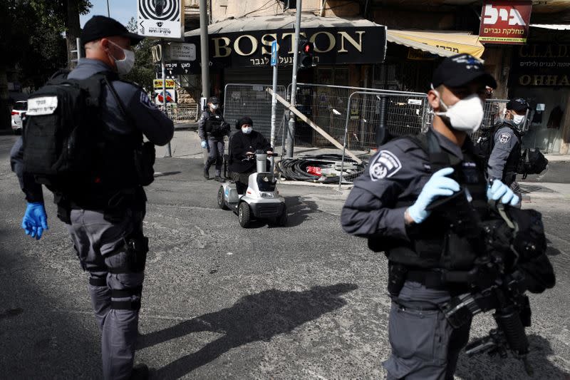 An ultra-Orthodox Jewish woman drives near Israeli police wearing masks as they patrol to enforce a national lockdown to fight the spread of the coronavirus disease (COVID-19) in Mea Shearim neighbourhood of Jerusalem