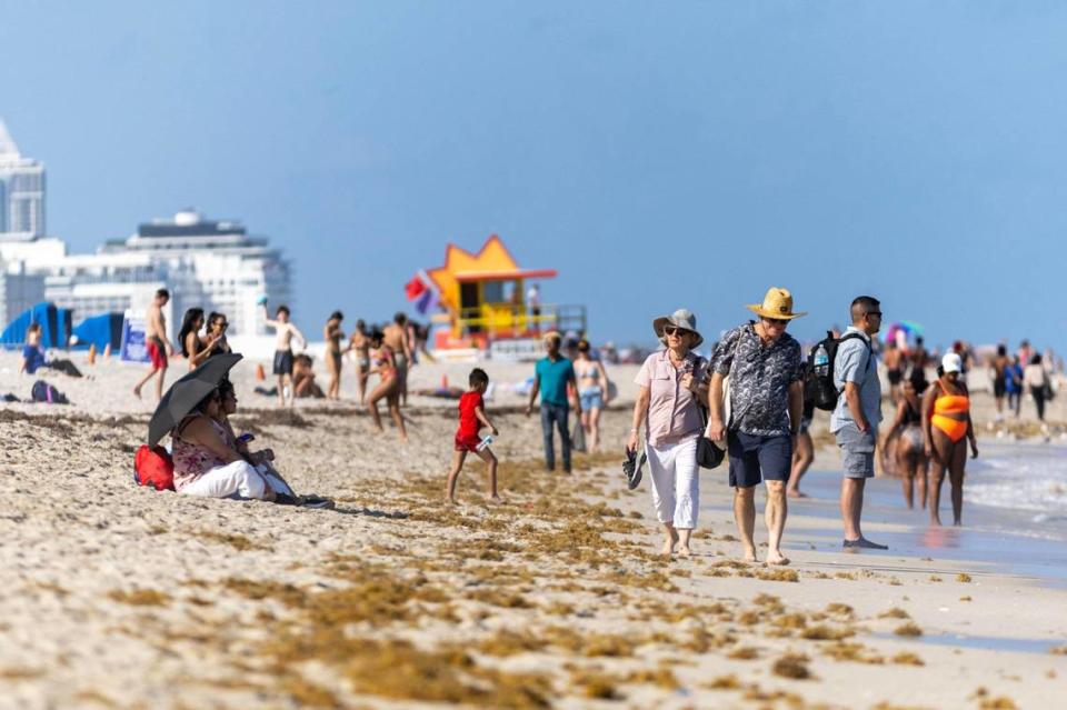 People walk and sit at the beach during spring break in Miami Beach on Friday, March 15, 2024.