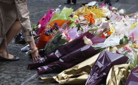 A woman lays a floral tribute to those who died in the Sydney cafe siege, near the site of the inciden,t in Martin Place December 16, 2014. REUTERS/Jason Reed