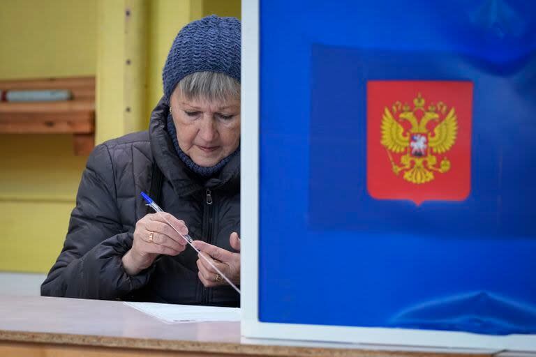 Una mujer comprueba si un bolígrafo escribe antes de rellenar su boleta para las elecciones presidenciales, en un centro de votación en San Petersburgo, Rusia, el 15 de marzo de 2024. (AP Foto/Dmitri Lovetsky)
