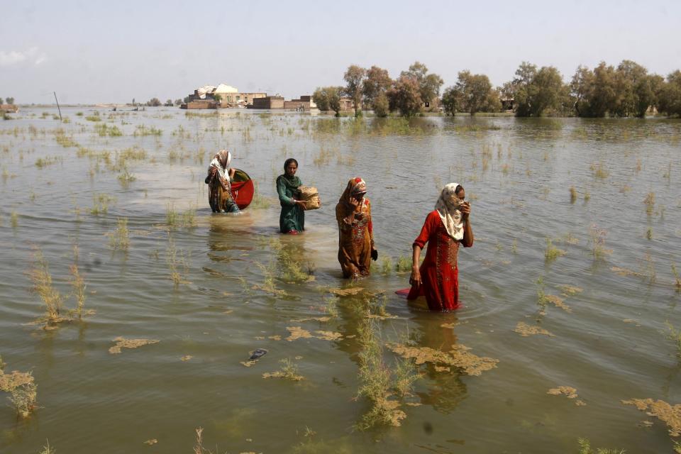 FILE - Pakistani women wade through floodwaters as they take refuge in Shikarpur district of Sindh Province, of Pakistan, Sept. 2, 2022. A major new United Nations report being released Monday, March 20, 2023, is expected to provide a sobering reminder that time is running out if humanity wants to avoid passing a dangerous global warming threshold. (AP Photo/Fareed Khan, File)