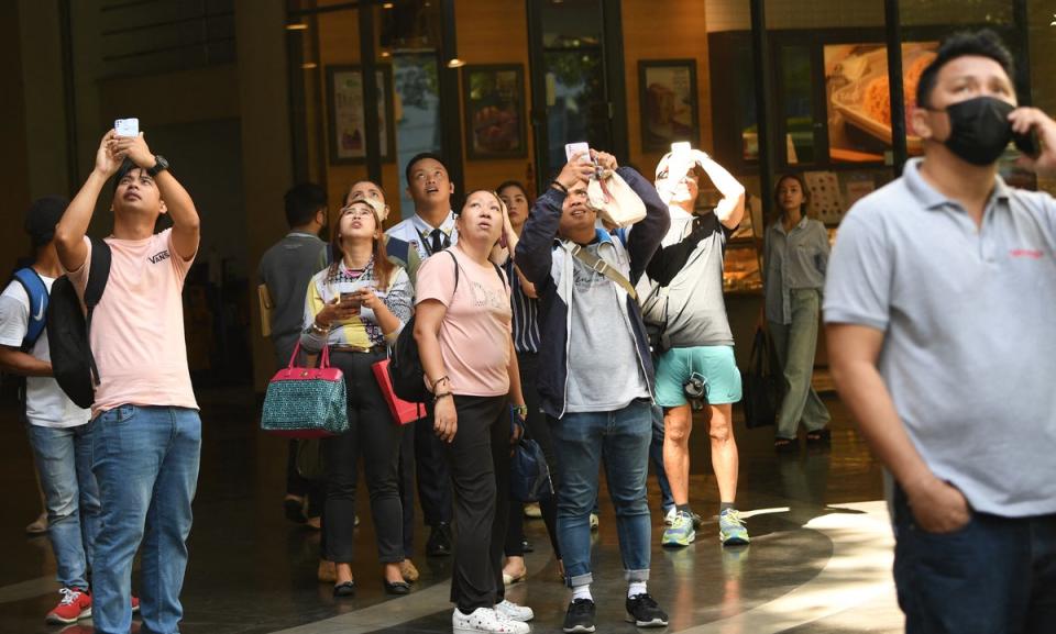 Onlookers gather to watch Alain Robert scaling a 47-storey building in Manila (AFP via Getty Images)