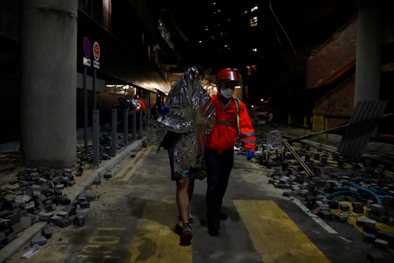 A protester is escorted by medical staff out of the Hong Kong Polytechnic University (PolyU) in Hong Kong