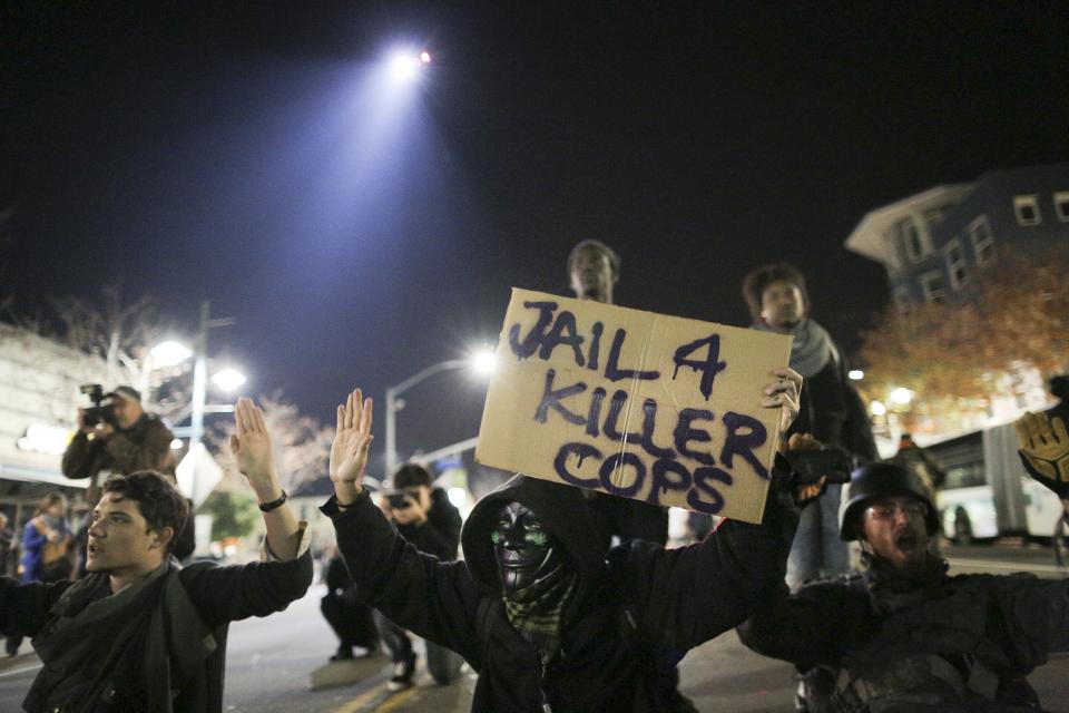 Protesters sit in the street as a police helicopter circles overhead during the second night of demonstrations in Emeryville, California, following the grand jury decision in the shooting of Michael Brown in Ferguson, Missouri, November 26, 2014. REUTERS/Elijah Nouvelage (UNITED STATES - Tags: CIVIL UNREST CRIME LAW)