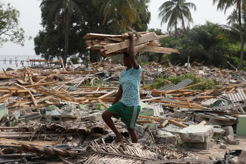 A girl carries wood planks on her head at the site of demolition in Lagos