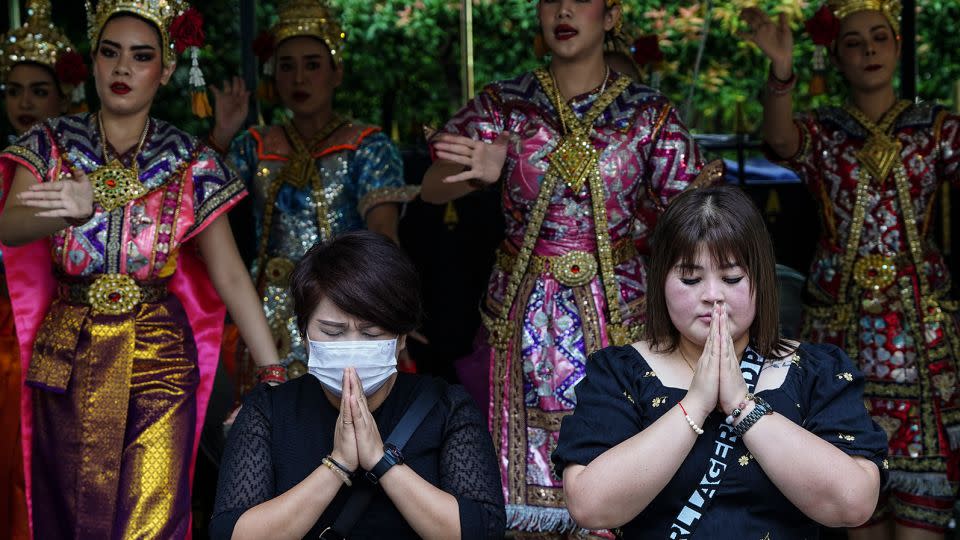 Chinese tourists pray in front of Thai dancers  at the Erawan Shrine in Bangkok, Thailand on September 22, 2023.  - Anusak Laowilas/NurPhoto/Getty Images