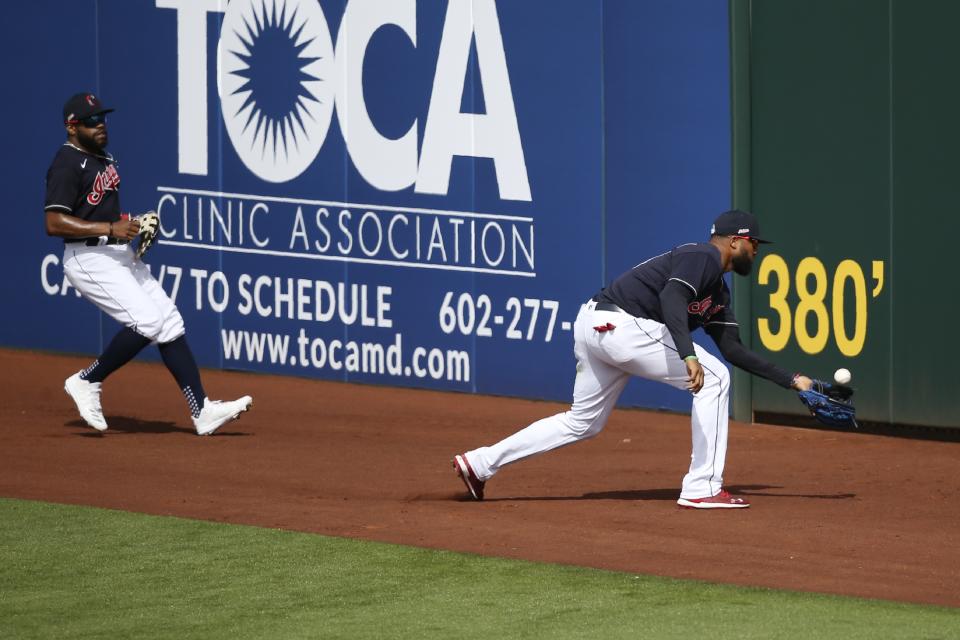 Cleveland Indians right fielder Domingo Santana, right, chases down a double hit by Los Angeles Dodgers' Tyler White as Indians center fielder Delino DeShields, left, watches during the fourth inning of a spring training baseball game Thursday, Feb. 27, 2020, in Goodyear, Ariz. (AP Photo/Ross D. Franklin)