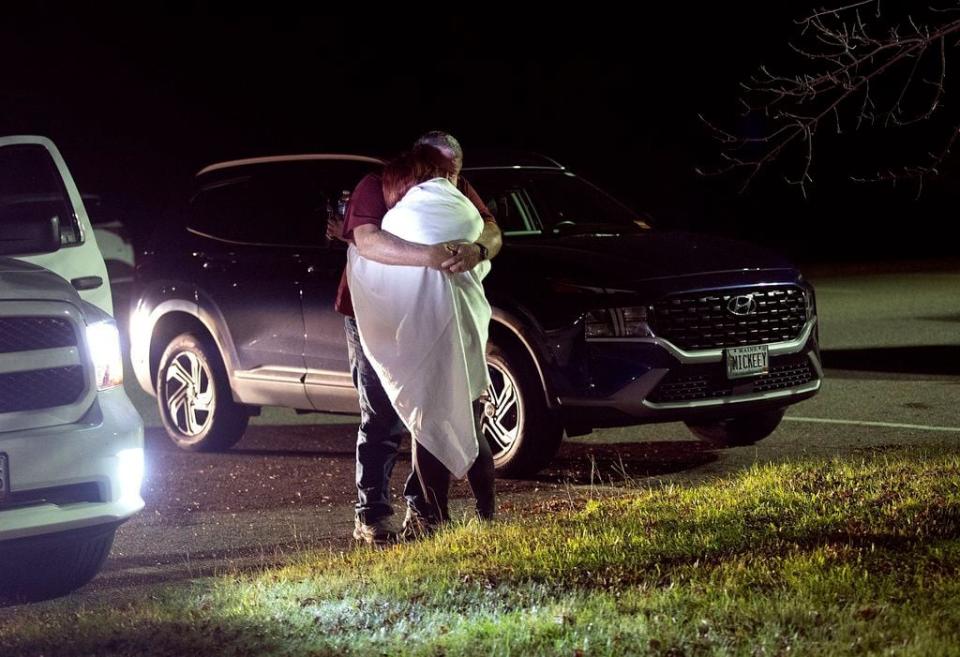 A woman is hugged by a man at a reunification center at Auburn Middle School, in Auburn, Maine, after shootings in Lewiston on Wednesday, Oct. 25, 2023.  (Derek Davis/Portland Press Herald via AP)