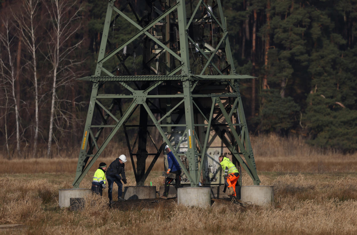 Arbeiter stehen an einem Strommast, der die nahe gelegene Tesla-Fabrik mit Strom versorgt und Opfer eines mutmaßlichen Brandanschlags wurde. Die 