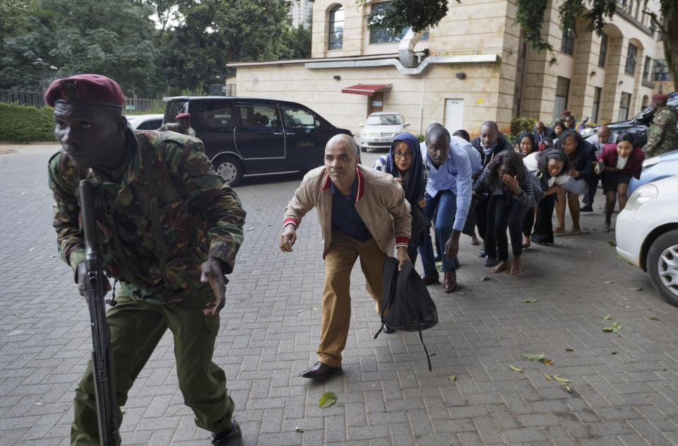 Civilians who had been hiding in buildings flee a hotel complex in Nairobi, Kenya, under the direction of a member of security forces, Jan. 15, 2019. (Photo: Ben Curtis/AP)