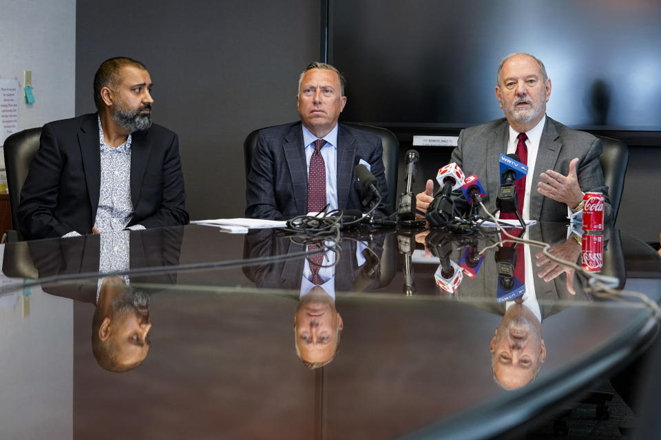 Attorneys Daniel Chamberlain, center, and Melvin Hewitt, Jr., right, along with family member Gurinder Johal announce a lawsuit in Indianapolis, Monday, April 11, 2022 on behalf of five families of the victims murdered in a mass shooting at the Indianapolis FedEx Ground facility on April 15, 2021. Johal's mother, Amarjeet Johal, was was one of eight workers killed in the shooting. (AP Photo/Michael Conroy)