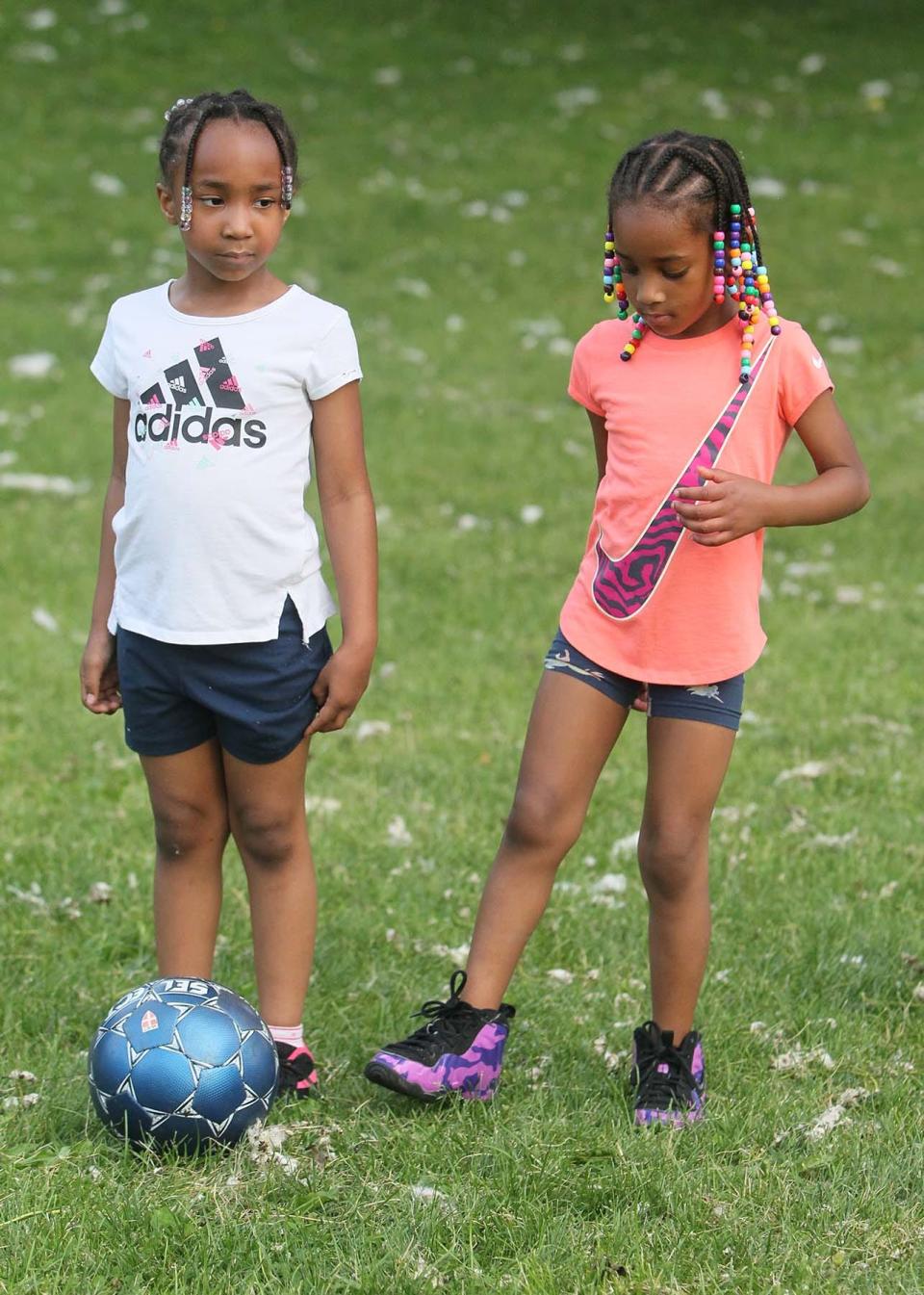 Bailey Bonds, 6, right, kicks the ball around her cousin Mya Thigpen, 6, during a soccer drill at the 15th annual free summer soccer camp put on the Akron Inner City Soccer Club at Hardesty Park in Akron on Monday. 