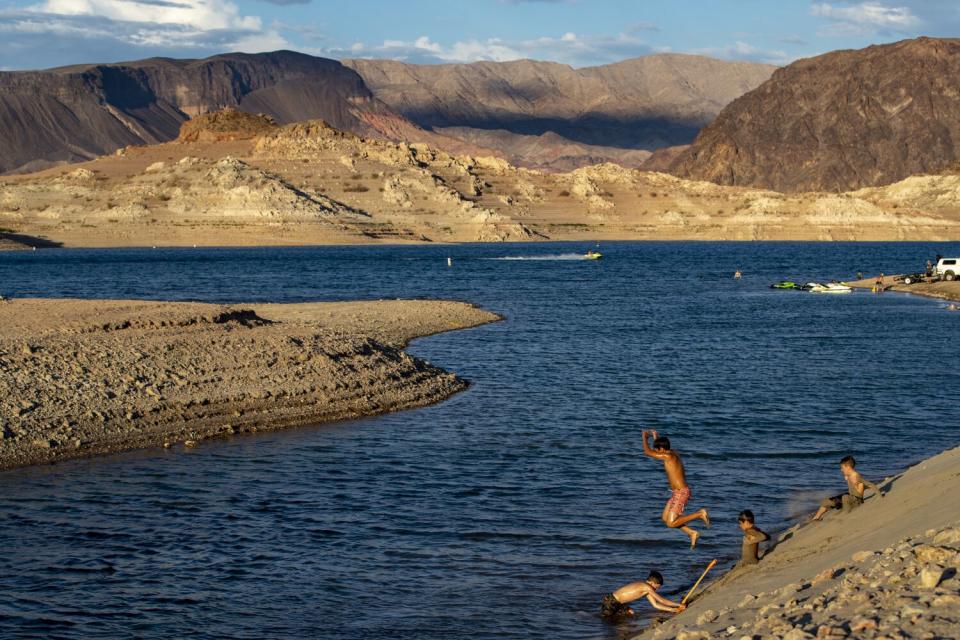 Children cool off jumping into a reservoir surrounded by dry banks and arid mountains.