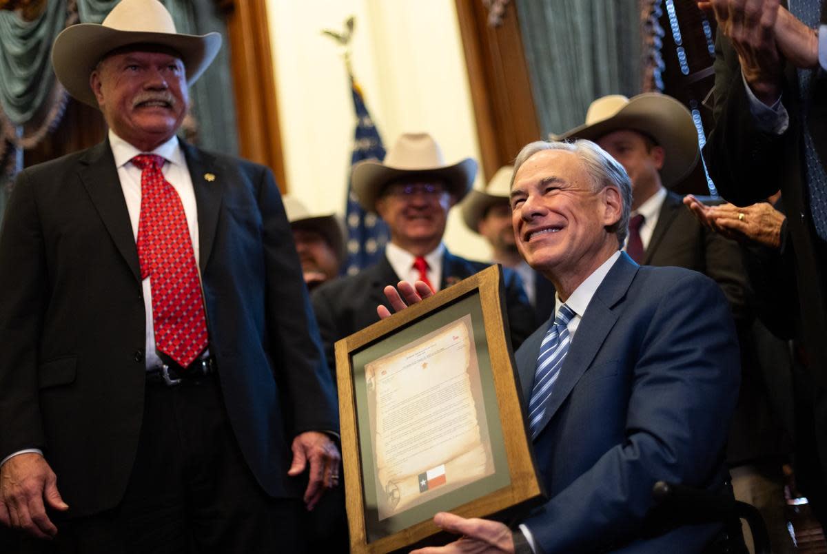 Gov. Greg Abbott poses with a framed letter from the Sheriffs' Association of Texas at the Texas Capitol in Austin on Wednesday, March 20, 2024. Abbott was presented with the letter after the association announced their support of his border policies.
