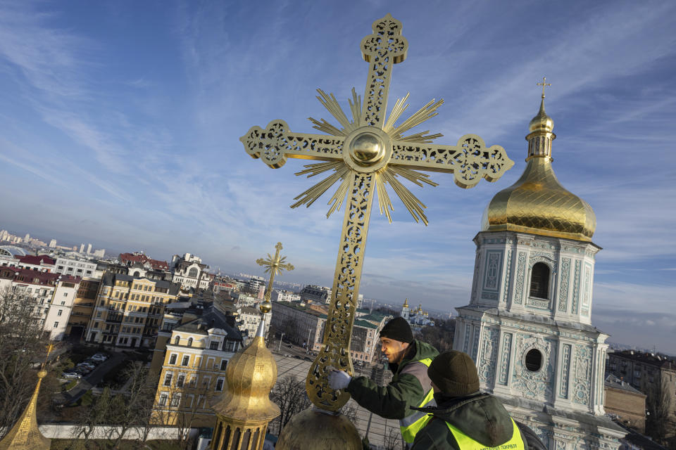 Ihor Kuzmenko, left, and Yuriy Maliuh altitude workers install a restored cross on a dome of Saint Sophia Cathedral in Kyiv, Ukraine, Thursday, Dec. 21, 2023. A UNESCO World Heritage site, the gold-domed St. Sophia Cathedral, located in the heart of Kyiv, was built in the 11th century and designed to rival the Hagia Sophia in Istanbul. (AP Photo/Evgeniy Maloletka)