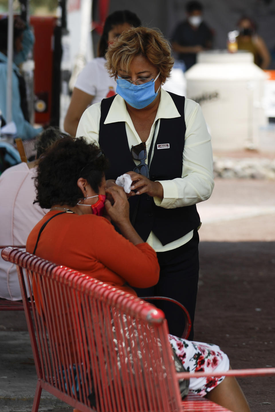 A worker tending a stand with information about funeral packages at a private cemetery steps away to comfort the relative of a hospitalized patient outside Las Americas General Hospital, which is treating patients with COVID-19 as well as those with other conditions, in Ecatepec, a suburb of Mexico City, Wednesday, May 20, 2020. Mexico City, one of the world's largest cities and the epicenter of the country's coronavirus epidemic, will begin a gradual reopening June 1, its mayor said Wednesday, even as daily new infections continued to set records.(AP Photo/Rebecca Blackwell)