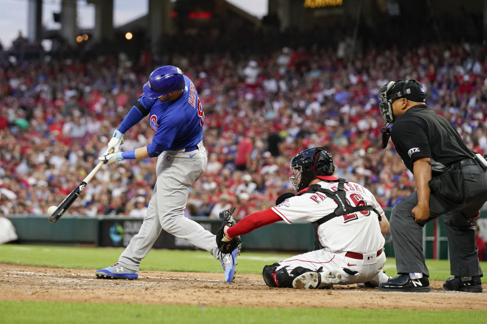 Chicago Cubs' Ian Happ, left, hits an RBI-single during the fifth inning of a baseball game against the Cincinnati Reds, Saturday, Aug. 13, 2022, in Cincinnati. (AP Photo/Jeff Dean)