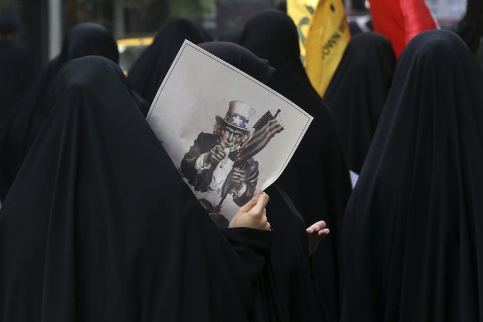 FILE - In this Oct. 4, 2015 file photo, a female Iranian demonstrator holds a poster showing a caricature of Uncle Sam during an annual anti-U.S. rally in front of the former U.S. Embassy in Tehran, Iran. (AP Photo/Vahid Salemi, File)