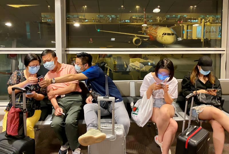 Mask-wearing passengers wait to board their flight at Kuala Lumpur International Airport