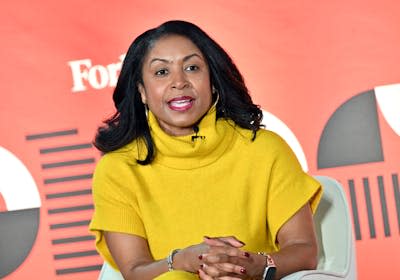 A Black woman is speaking as she sits in a chair on stage.