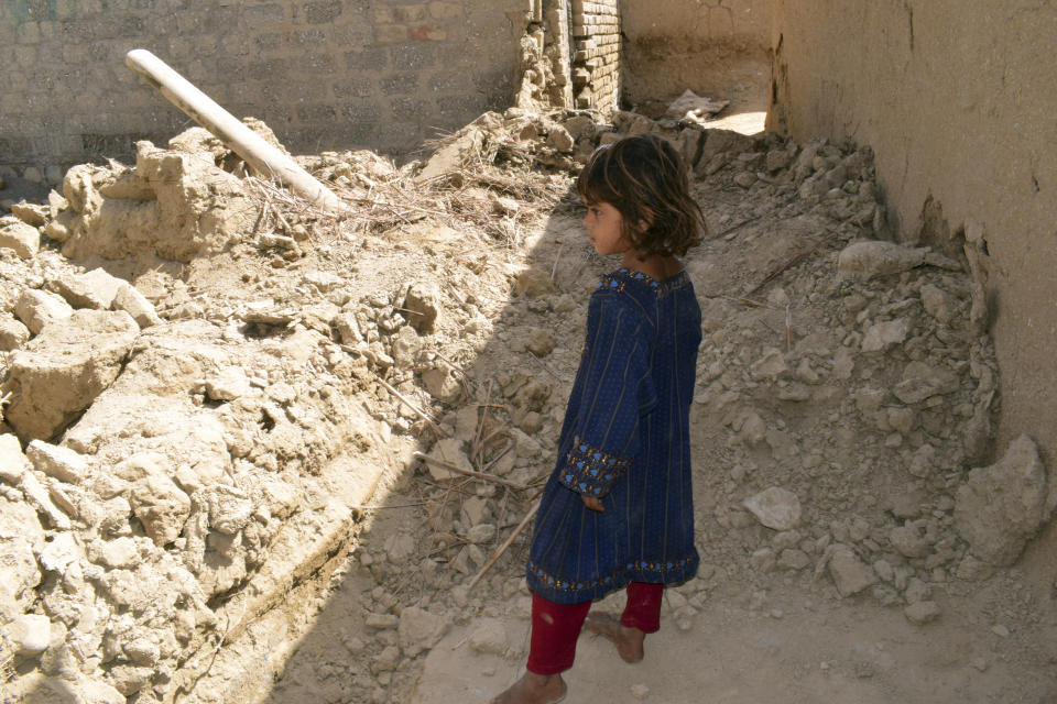 A girl looks at a damaged house following an earthquake in Harnai, about 100 kilometers (60 miles) east of Quetta, Pakistan, Thursday, Oct. 7, 2021. The powerful earthquake collapsed at least one coal mine and dozens of mud houses in southwest Pakistan early Thursday. (AP Photo/Arshad Butt)