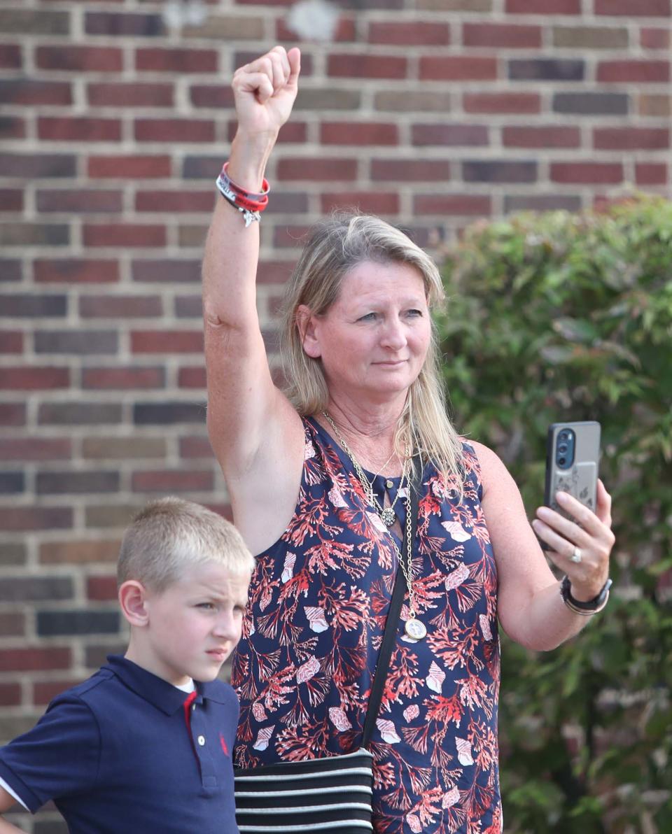 Donna Benfer, Matthew Parisi's aunt, raises her fist in recognition of "Parisi Strong" as she stands next to Conner Conley, 7, Parisi's cousin, while motorcyclists pay tribute to Parisi on Sunday.