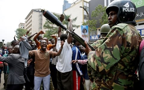 Police watch the cheering crowd outside the court in Nairobi - Credit: BAZ RATNER/Reuters