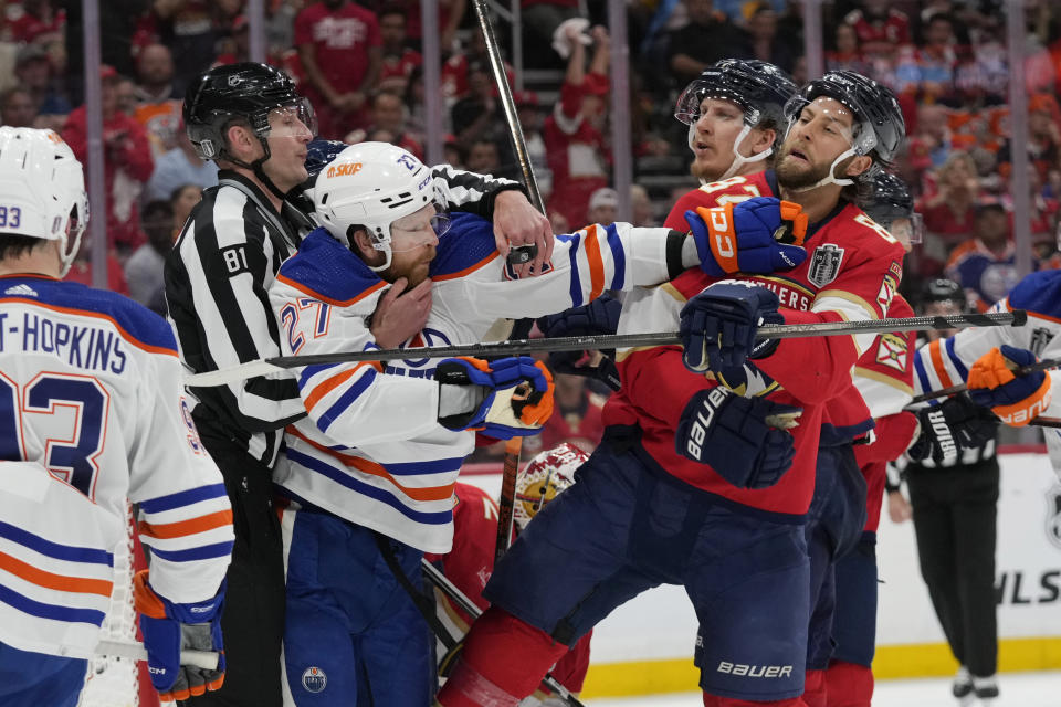 Edmonton Oilers defenseman Brett Kulak (27) throws a punch at Florida Panthers center Kevin Stenlund, front right, during the third period of Game 2 of the NHL hockey Stanley Cup Finals, Monday, June 10, 2024, in Sunrise, Fla. (AP Photo/Wilfredo Lee)