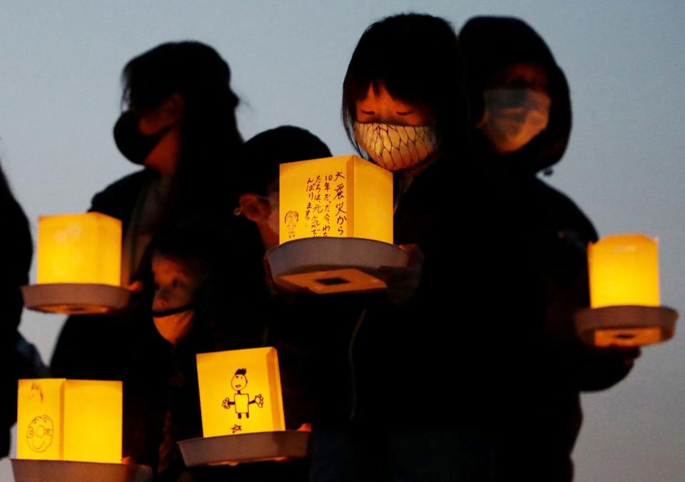 Local residents hold lanterns with messages for earthquake and tsunami victims in Yamada, Iwate prefecture on March 11, 2021.