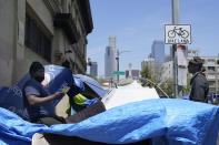 LA CAN outreach worker and human rights organizer, Steve Richardson, who goes by General Dogon, reaches out to homeless people in the Skid Row area of Los Angeles Friday, July 22, 2022. “Police should be nowhere around outreach. You can’t be the provider of services as well as the jailer,” said Pete White, the founder and executive director of the Los Angeles Community Action Network. “My hope ... is that those resources that go to the police department are actually pointed towards real solutions.” (AP Photo/Damian Dovarganes)