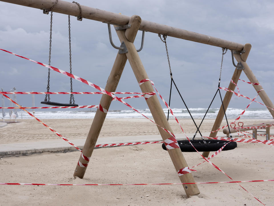 This Friday, March 20, 2020 photo shows swings at Tel Aviv's beachfront wrapped in tape to prevent public access. Israel has reported a steady increase in confirmed cases despite imposing strict travel bans and quarantine measures more than two weeks ago. Authorities recently ordered the closure of all non-essential businesses and encouraged people to work from home. (AP Photo/Oded Balilty)