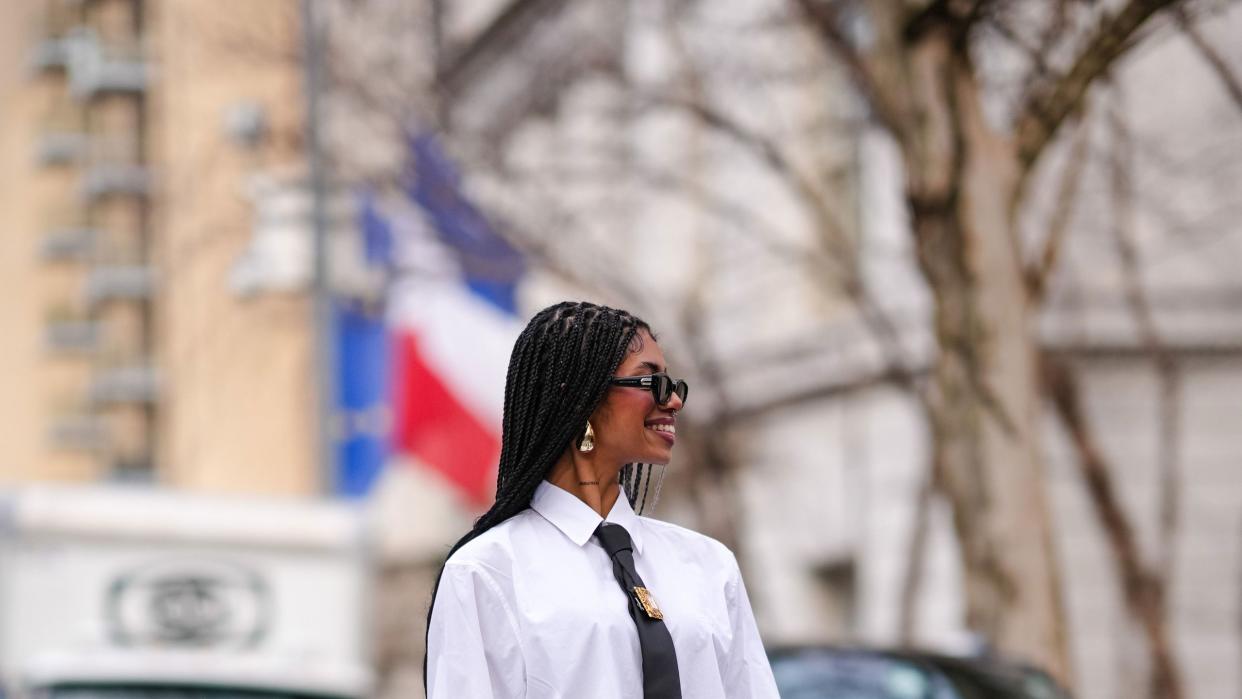 a person in a white shirt and black skirt walking across a street