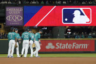 FILE - Seattle Mariners gather as the MLB logo is shown during a review of an attempted catch by right fielder Mitch Haniger of a ball hit by Tampa Bay Rays' Ji-Man Choi that was originally called an out during the ninth inning of a baseball game Friday, June 18, 2021, in Seattle. The call was overturned. The Mariners won 5-1. The clock ticked down toward the expiration of Major League Baseball’s collective bargaining agreement at 11:59 p.m. EST Wednesday night, Dec. 1, 2021, and what was likely to be a management lockout ending the sport’s labor peace at over 26 1/2 years. (AP Photo/Ted S. Warren)