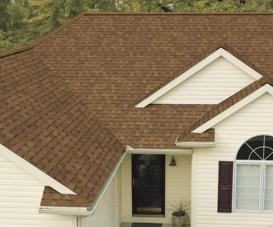 Light brown architectural roof shingles on a cream colored house