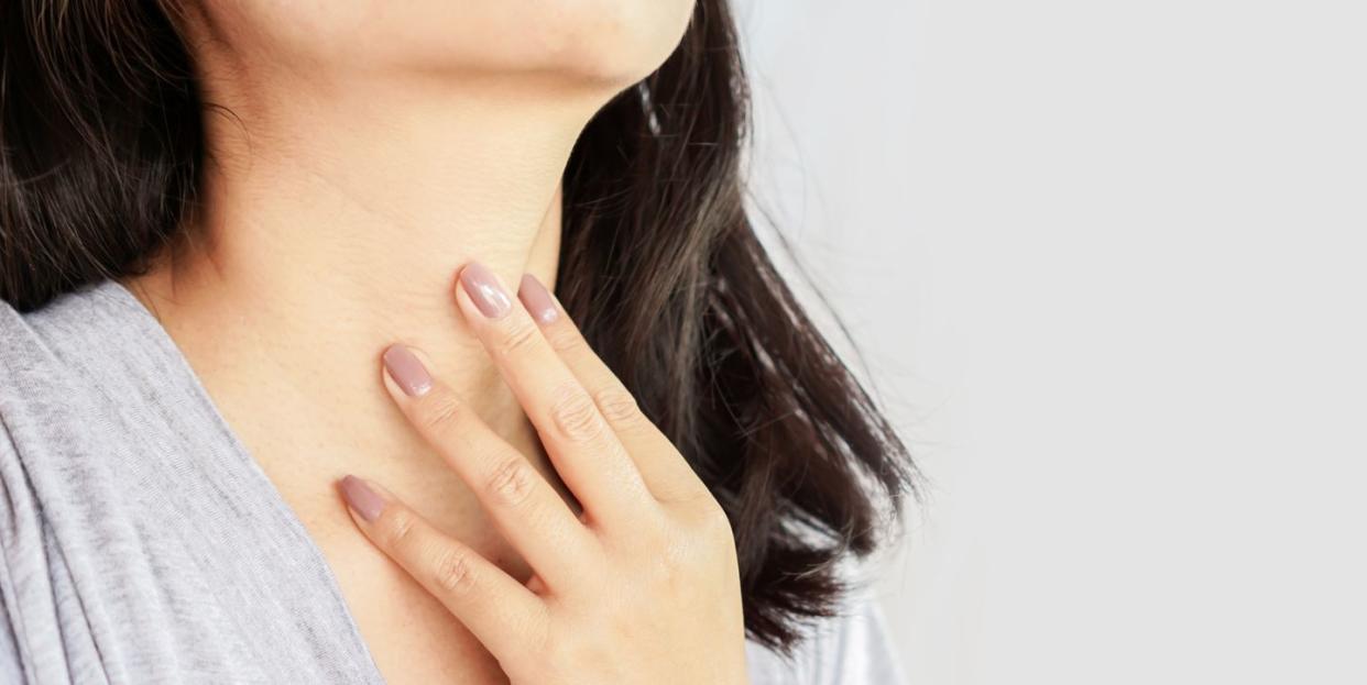 woman hand self checking thyroid gland on her neck