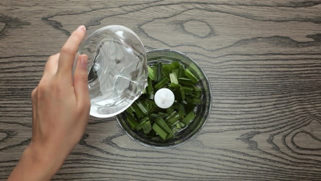 Adding water to food processor with pandan leaves inside