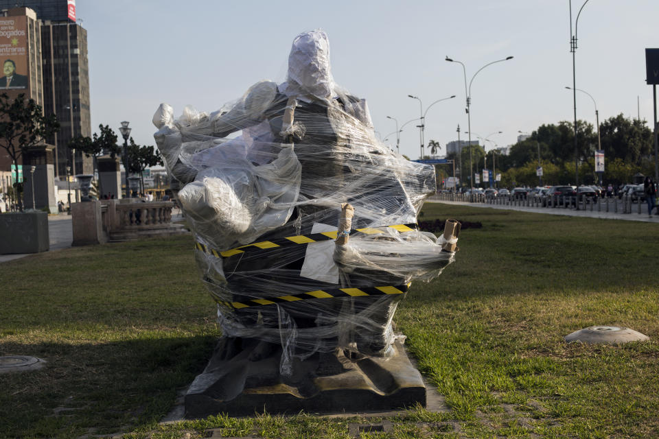 A bronze statue of an Andean farmer with two bulls plowing the land, is wrapped in plastic, located on the Paseo de los Heroes boulevard in Lima, Peru, Saturday, Nov. 21, 2020. Target of attacks in other countries during social and political protests, historical monuments and statues in Peru's capital came out of recent street demonstrations practically intact. (AP Photo/Rodrigo Abd)