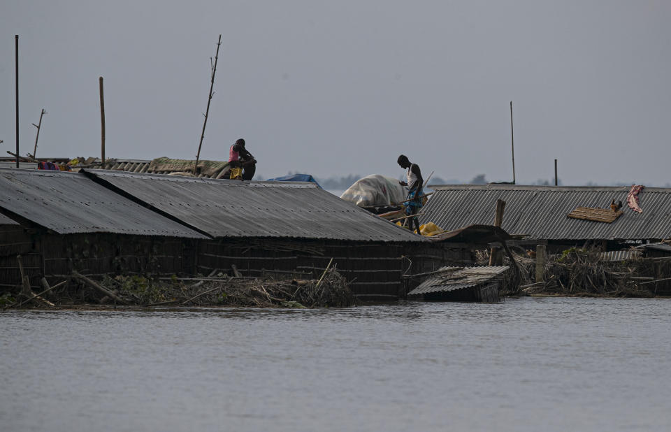 Flood affected people tare seen on the roof of their partially submerged houses along river Brahmaputra in Morigaon district, Assam, India, Thursday, July 16, 2020. Floods and landslides triggered by heavy monsoon rains have killed dozens of people in this northeastern region. (AP Photo/Anupam Nath)