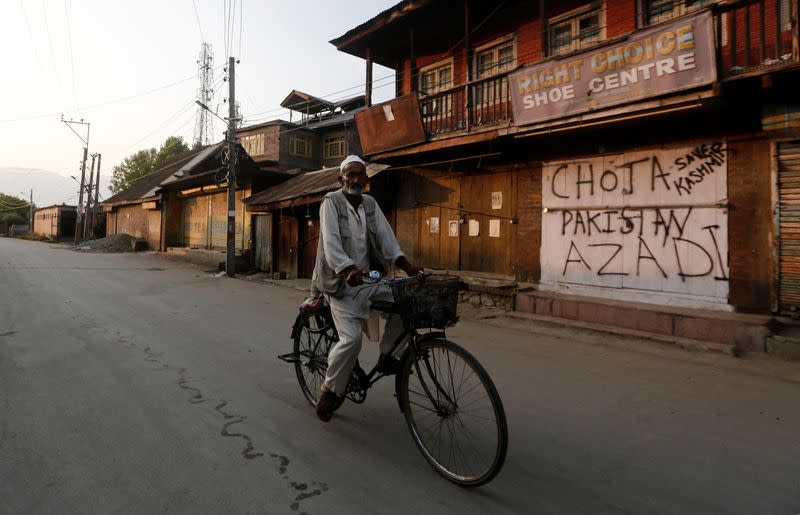 Kashmiri man rides his bicycle past a shop in Anchar neighbourhood in Srinagar