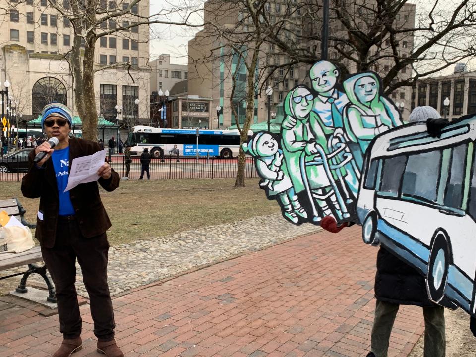 In Providence's Burnside Park, Rochelle Lee of RI Transit Riders speaks at a Feb. 10 Transit Equity Day rally for better transit service. Advocates have spoken out against RIPTA's plan to move its hub from Kennedy Plaza, background, to a location near the state's Family Court on Dorrance Street.